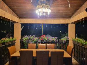 mesa de comedor con sillas, lámpara de araña y flores en Vila Magnolia, en Curtea de Argeş