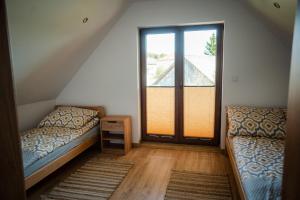 a attic room with two beds and a large window at Domki przy Alei in Krasnobród