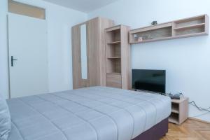a bedroom with a bed and a flat screen tv at Gerardus Apartmani in Vršac