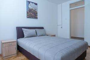 a bedroom with a bed with a blue comforter at Gerardus Apartmani in Vršac