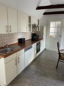 a kitchen with white cabinets and a sink at FeWo Elbdeichliebe in Boizenburg