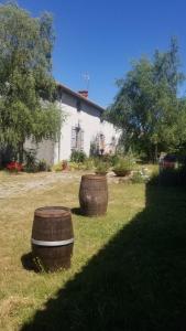 two large barrels sitting in the grass in front of a house at Chambres et gîte dans un lieu calme et champêtre in Gourgé