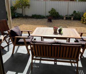 a wooden table with two chairs and a table with flowers on it at Avino Rutherglen in Rutherglen