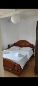 uma cama com uma estrutura de madeira e lençóis brancos em Villa Medi em Lesina