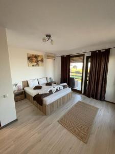 a bedroom with a large bed and a large window at Hacienda del Mar'a in Vama Veche