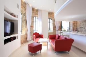 a living room with two red chairs and a tv at The White House Jerusalem סוויטת הבית הלבן ירושלים in Jerusalem