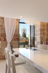 a dining room with a white table and chairs and a window at The White House Jerusalem סוויטת הבית הלבן ירושלים in Jerusalem