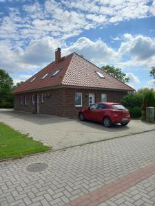 a red car parked in front of a brick house at Bi Grete vörn in Dornum