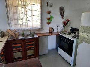 a small kitchen with a stove and a sink at Charly's place in Calibishie