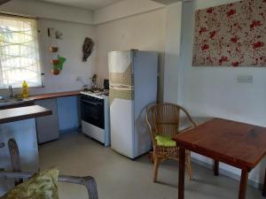 a kitchen with a refrigerator and a table in it at Charly's place in Calibishie