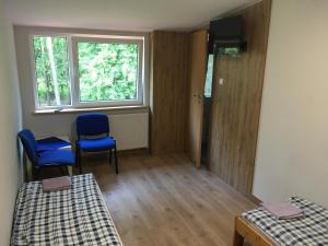 a room with two beds and two chairs and a window at Rezydencja pod Gwiazdami in Legarda