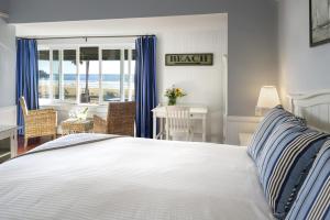 Cette chambre comprend un lit avec des rideaux bleus et un bureau. dans l'établissement Newport Beach Hotel, à Newport Beach
