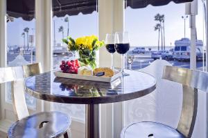un tavolo con un piatto di cibo e due bicchieri di vino di Newport Beach Hotel a Newport Beach
