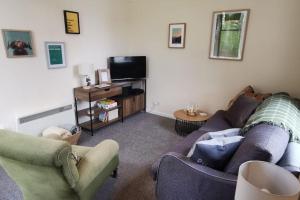 a living room with a couch and a tv at *Cool, cosy cottage in the heart of the Highlands* in Kincraig