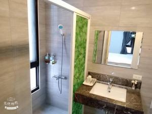 ein Bad mit einem Waschbecken und einer Dusche mit einem Spiegel in der Unterkunft 宜蘭頭城空空如也Kong Kong in Toucheng