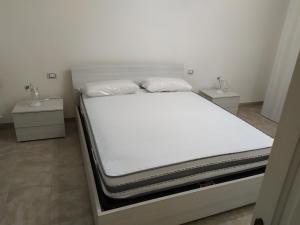 Una cama con sábanas blancas y almohadas. en Villa Aurora 1, en Torre Lapillo