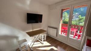 a room with a desk and a television and a window at la foux d'allos au pied des pistes in La Foux