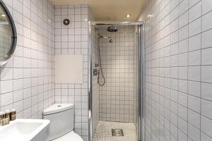 a white tiled bathroom with a shower and a toilet at Modern Victoria Park Apartment in London