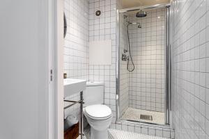 a white bathroom with a toilet and a shower at Modern Victoria Park Apartment in London