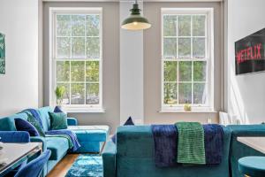 a living room with blue couches and two windows at Stunning Abode - Sleeps 10 - Parking in Bristol