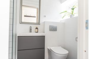 a white bathroom with a toilet and a sink at Ferielejlighed Næstved in Næstved