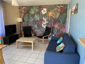 un salon avec un canapé bleu et une télévision dans l'établissement Océanis face océan, à Biscarrosse-Plage
