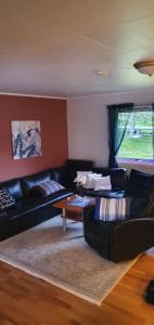 a living room with black couches and a coffee table at Nydelig utsikt, egen leilighet med to parkeringer in Movik