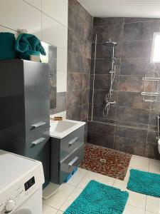 ein Badezimmer mit einem Waschbecken und einer Dusche mit blauen Teppichen in der Unterkunft Studio les trois perles in Les Anses-dʼArlets