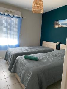Océanis face océan في بيسكاروس-بلاج: غرفة نوم عليها سرير ومخدة خضراء