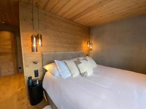 een slaapkamer met een wit bed en houten wanden bij Chalet 7 Luxury Chalet with Cinema room in Crans-Montana