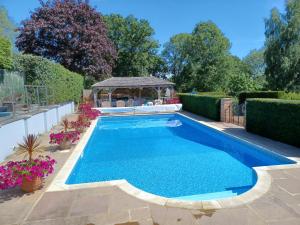 een zwembad met een tuinhuisje in de tuin bij Rookwood Farmhouse B&B in Newbury