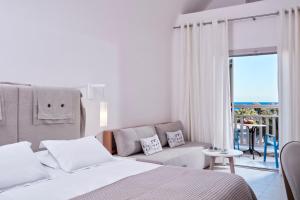 1 dormitorio con cama, sofá y balcón en Santo Miramare Beach Resort en Perivolos