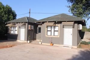 ein kleines Haus mit zwei weißen Türen und einem Dach in der Unterkunft Global Guest House in Kasane