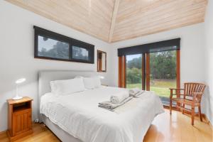 a bedroom with a bed and a chair and a window at Yallingup Retreat - Romantic Country Retreat for Couples in Yallingup