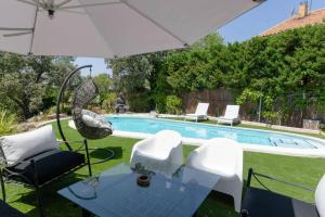 - une piscine avec une table, des chaises et un parasol dans l'établissement La Amapola, à Valdemorillo