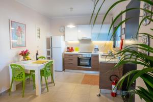 une cuisine avec une table blanche et des chaises vertes dans l'établissement Melibel House, à Rhodes