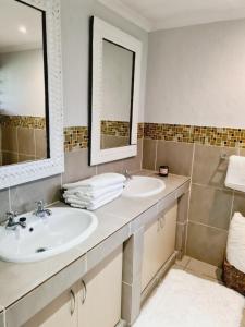 a bathroom with two sinks and two mirrors at Finna's lovely 1-bedroom open plan vacation home. in Germiston