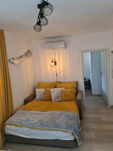 Un dormitorio con una cama con sábanas amarillas y una lámpara de araña. en EDA Beach Galerius Apartman, en Siófok