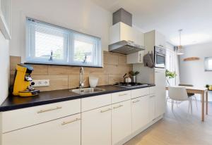 a kitchen with white cabinets and a sink at Duin17 in Zoutelande