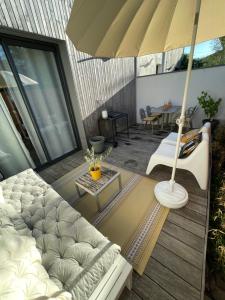 eine Terrasse mit einer Couch und einem Sonnenschirm in der Unterkunft Maison Candau in Pessac
