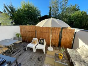 eine Terrasse mit Sonnenschirm und Tisch und Stühlen in der Unterkunft Maison Candau in Pessac