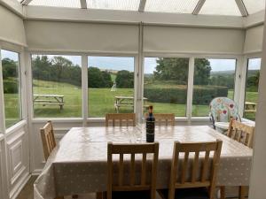 a dining room with a table and chairs and windows at Ploughmans Cottage, St Florence, Tenby in Saint Florence