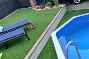 a artificial grass yard with a bench next to a swimming pool at Casa Joana in Canyelles