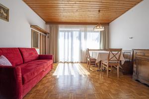 a living room with a red couch and a table at Apartments Praruf in Selva di Val Gardena