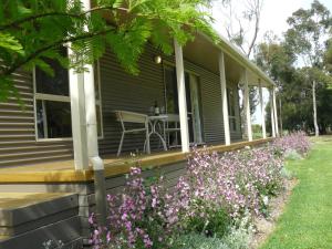 eine Veranda eines Hauses mit einem Tisch und Blumen in der Unterkunft Camawald Coonawarra Cottage B&B in Coonawarra