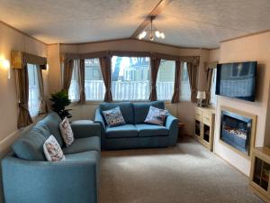 a living room with two blue couches and a television at Mudeford Beach Lodge in Mudeford