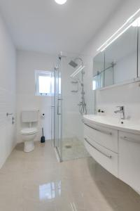 een witte badkamer met een douche en een toilet bij Premium apartment with beautiful sea view, short walk to the sea in Opatija