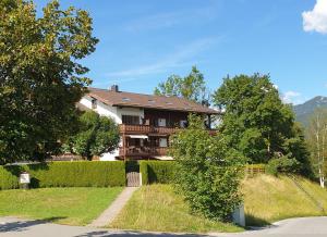 ein Haus auf einem Hügel mit einem Zaun und Bäumen in der Unterkunft Haus Abendsonne Familie Druxes in Krün