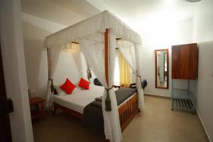 a bedroom with a canopy bed with red pillows at Ayla Homes in Madikeri