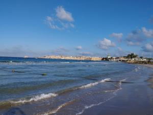a beach with the ocean and buildings in the background at Sweet Little House in Acre